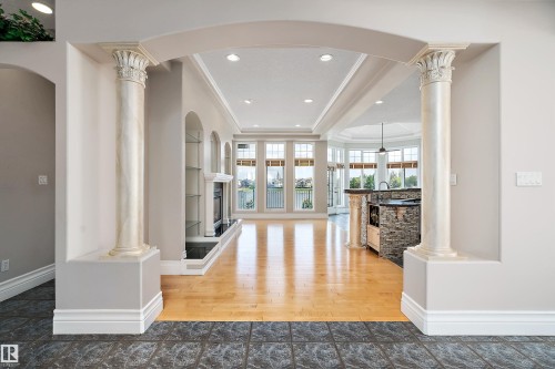 Arched entryway with decorative columns showcasing a fireplace, built-in shelving, and large windows - 16103 89 Street, Edmonton, AB - Indoor Photo Showing Other Room
