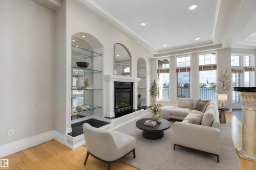 Living area featuring a fireplace with a white mantel, built-in arched display shelving with glass, light wood-finish flooring, and a series of large windows - 16103 89 Street, Edmonton, AB - Indoor Photo Showing Living Room With Fireplace