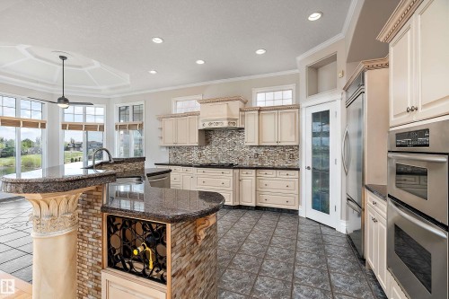 Gourmet kitchen featuring a large central island with integrated wine storage, dual wall ovens, and stainless steel appliances - 16103 89 Street, Edmonton, AB - Indoor Photo Showing Kitchen With Upgraded Kitchen