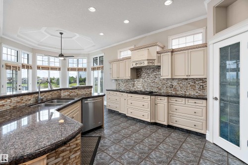Gourmet kitchen featuring a large curved island with a double basin stainless steel sink, granite countertops, and light-toned cabinetry - 16103 89 Street, Edmonton, AB - Indoor Photo Showing Kitchen With Double Sink With Upgraded Kitchen