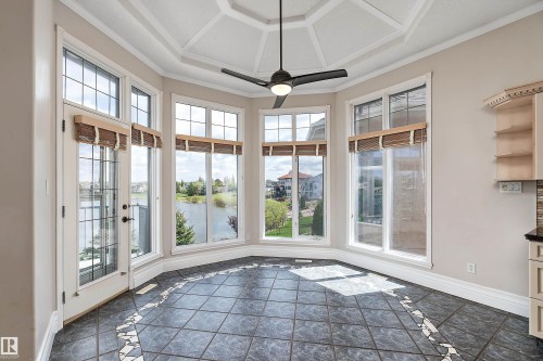 Spacious bay window area featuring dark tile flooring with a decorative border, multiple large windows, and a glass-paneled door - 16103 89 Street, Edmonton, AB - Indoor Photo Showing Other Room