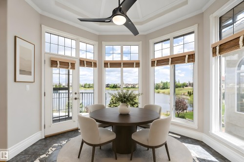 Bay window dining area featuring expansive window panes, patterned floor tile, a modern ceiling fan, and access to an exterior balcony - 16103 89 Street, Edmonton, AB - Indoor Photo Showing Dining Room