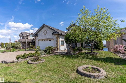 Stone exterior with a two-car garage, complemented by a gravel driveway and a lush front lawn - 16103 89 Street, Edmonton, AB - Outdoor