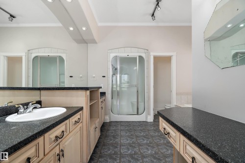 Bathroom featuring a built-in vanity with an integrated sink, dark speckled countertops, and light wood cabinetry with dark hardware - 16103 89 Street, Edmonton, AB - Indoor Photo Showing Bathroom