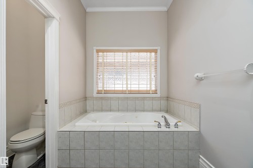 Built-in soaking tub with deck-mounted fixtures, surrounded by neutral-toned tile - 16103 89 Street, Edmonton, AB - Indoor Photo Showing Bathroom
