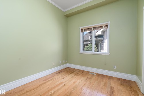 Bright room featuring wood-finish flooring, light green walls, a white-framed window, and crown molding - 16103 89 Street, Edmonton, AB - Indoor Photo Showing Other Room