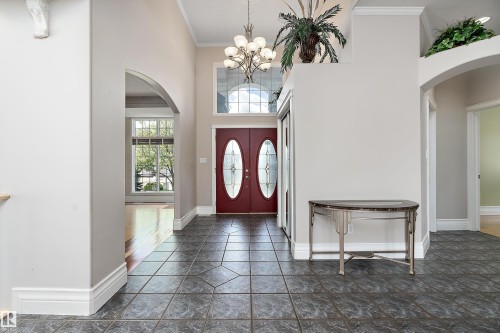 Grand entryway featuring rich red double doors with oval glass inserts, and a transom window above - 16103 89 Street, Edmonton, AB - Indoor Photo Showing Other Room