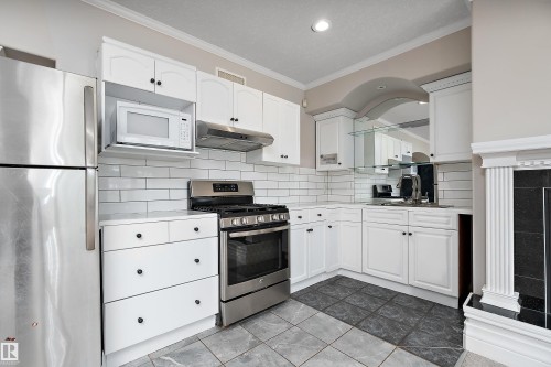 Kitchen featuring white cabinetry, stainless steel appliances, a subway tile backsplash, and a built-in microwave - 16103 89 Street, Edmonton, AB - Indoor Photo Showing Kitchen