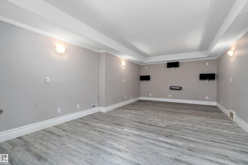 Spacious room featuring gray wood-finish flooring, light gray walls, and white baseboards - 16103 89 Street, Edmonton, AB - Indoor Photo Showing Other Room