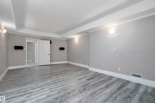 Spacious room featuring wood-finish flooring, light gray walls, white baseboards, and crown molding - 16103 89 Street, Edmonton, AB - Indoor Photo Showing Other Room