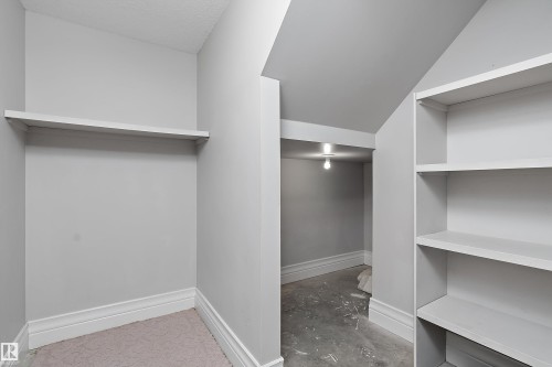 Interior storage area featuring a built-in shelving unit, a wall-mounted shelf, light gray wall paint, and white baseboards - 16103 89 Street, Edmonton, AB - Indoor