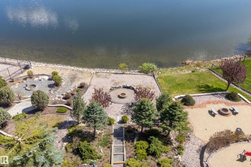 Waterfront property featuring multiple terraced outdoor spaces, a stone fire pit area, a paver patio, a manicured lawn, and mature landscaping - 16103 89 Street, Edmonton, AB - Outdoor With View