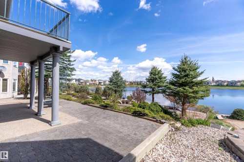 Paved patio area featuring architectural columns supporting an upper-level balcony with metal railings - 16103 89 Street, Edmonton, AB - Outdoor With Body Of Water With View