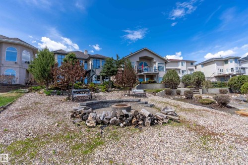 Expansive backyard featuring a stone-lined fire pit, tiered landscaping, and mature plantings - 16103 89 Street, Edmonton, AB - Outdoor