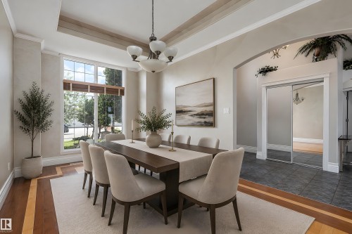Spacious dining area featuring a prominent multi-pane window, wood-finish flooring with a distinctive border, and a classic chandelier - 16103 89 Street, Edmonton, AB - Indoor Photo Showing Dining Room