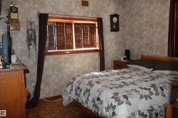 Window with wood-finish shutters, patterned wallpaper, wood-finish flooring, and a built-in wall clock. - 
