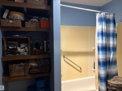 Bathroom featuring a built-in tub with a grab bar, a shower surround, and integrated shelving. - 