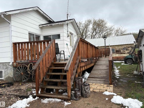 Rear exterior featuring a wood deck with railing and an accessible ramp entry - 125 56524 Rng Rd 52A, Lindbergh, AB 