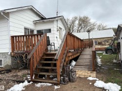Rear exterior featuring a wood deck with railing and an accessible ramp entry - 