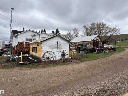 Property featuring multiple outbuildings, including a white-sided structure with a pitched roof and a log building with a metal roof. - 125 56524 Rng Rd 52A, Lindbergh, AB 