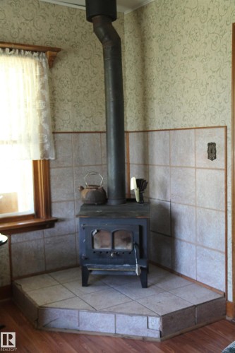 Corner wood-burning stove with a tile surround and hearth. - 125 56524 Rng Rd 52A, Lindbergh, AB 