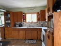 Kitchen featuring abundant wood-finish cabinetry, a ceramic tile backsplash, a built-in oven, and a double basin sink beneath a window. - 125 56524 Rng Rd 52A, Lindbergh, AB 