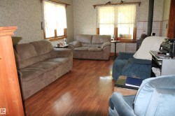 Room featuring wood-finish flooring, patterned wallpaper, and multiple windows with wood trim. - 