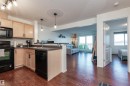 Kitchen featuring light brown cabinetry, black appliances, open floor plan, dark countertops, and decorative backsplash - 303 5951 165 Avenue, Edmonton, AB 