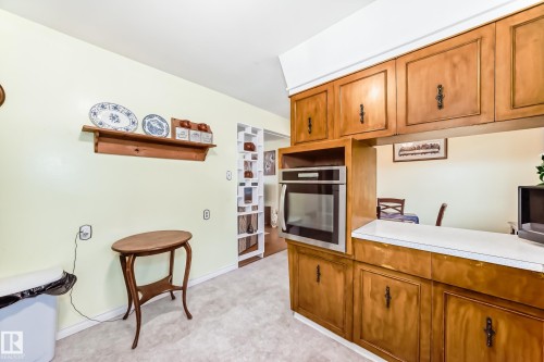 Kitchen featuring wood-finish cabinetry with inset panels and dark hardware, integrated stainless steel oven, and a white laminate countertop - 8006 159 Street, Edmonton, AB 