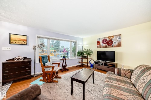 Spacious living area featuring expansive windows, wood-finish flooring, a light-toned ceiling, a built-in wall niche, and neutral wall paint - 8006 159 Street, Edmonton, AB 