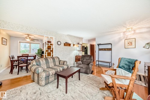 Bright living area featuring wood-finish flooring and a textured accent wall - 8006 159 Street, Edmonton, AB 