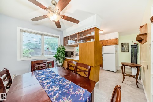 Dining area featuring a ceiling fan with integrated lighting, a large window, and light gray wall paint - 8006 159 Street, Edmonton, AB 