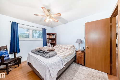 Bedroom featuring wood-finish flooring, a ceiling fan with integrated lighting, and a window with white trim - 8006 159 Street, Edmonton, AB 