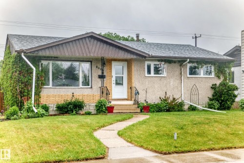 Front exterior showcasing a composite shingle roof, stucco and brick facade, white framed windows, and a curved concrete walkway - 8006 159 Street, Edmonton, AB 
