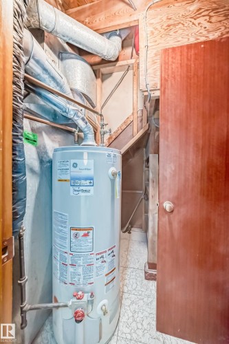 Utility area featuring a water heater, exposed ductwork, copper piping, and wood-paneled walls - 8006 159 Street, Edmonton, AB 