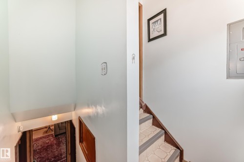 Staircase featuring wood-finish railing and tile treads with painted risers - 8006 159 Street, Edmonton, AB 