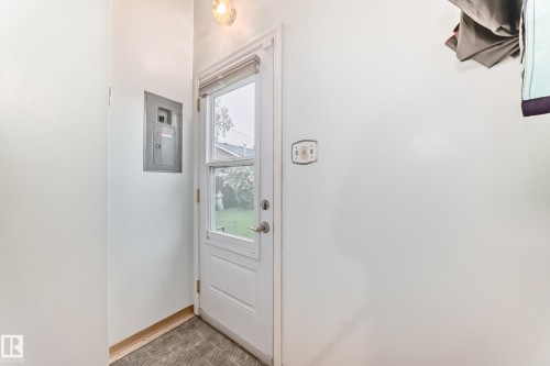 Rear entry door with a full-lite glass panel, recessed blinds, and a brushed nickel door handle - 8006 159 Street, Edmonton, AB 