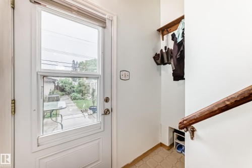 Entryway featuring a glass-paneled door, tiled flooring, wood handrail, and integrated shelving - 8006 159 Street, Edmonton, AB 