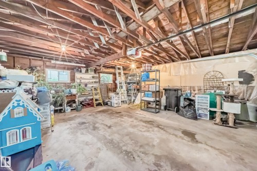 Spacious garage featuring exposed wood beam ceiling, concrete flooring, and multiple windows providing natural light - 8006 159 Street, Edmonton, AB 