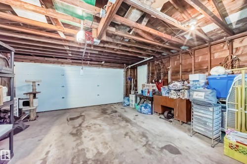 Garage featuring an overhead door, exposed wood framing, concrete flooring, and an overhead light fixture - 8006 159 Street, Edmonton, AB 