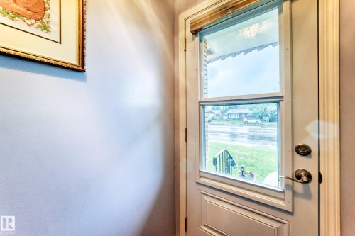 Entry door featuring an integrated full-light storm door and classic brass-finish hardware - 8006 159 Street, Edmonton, AB 