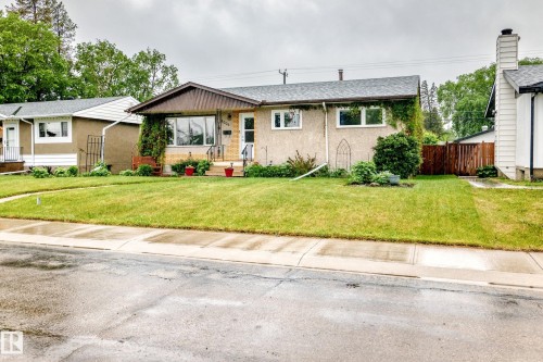 Stucco exterior with a peaked roofline, mature front yard landscaping, and a fenced side yard - 8006 159 Street, Edmonton, AB 