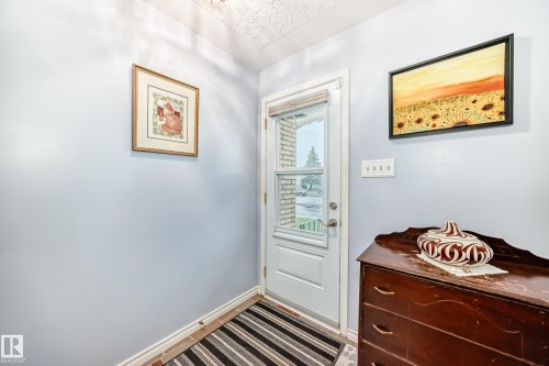 White entry door with upper glass panel, complemented by a light blue wall finish and patterned ceiling texture - 8006 159 Street, Edmonton, AB 