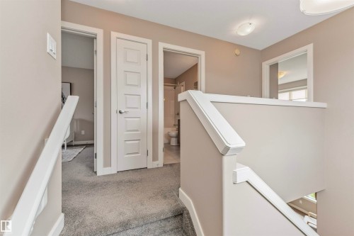 Carpeted staircase and landing with light gray walls, white trim, white paneled doors, and a ceiling-mounted light fixture - 22124 85 Avenue, Edmonton, AB - Indoor Photo Showing Other Room