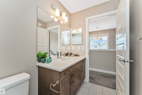 Bathroom vanity featuring a single integrated sink, white countertop, and dark wood-finish cabinetry - 22124 85 Avenue, Edmonton, AB - Indoor Photo Showing Bathroom