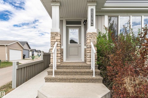 Front entrance featuring stone veneer columns, exposed aggregate steps, a full-lite entry door, and a white handrail - 22124 85 Avenue, Edmonton, AB - Outdoor