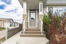 Front entrance featuring stone veneer columns, exposed aggregate steps, a full-lite entry door, and a white handrail - 22124 85 Avenue, Edmonton, AB  - Outdoor 