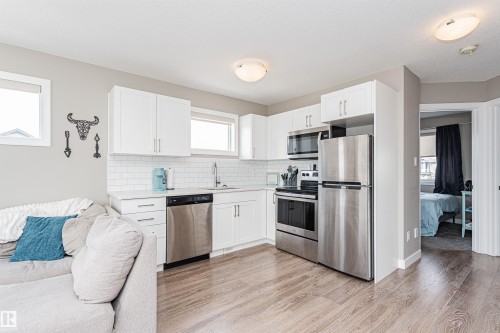 Kitchen featuring white shaker-style cabinetry, stainless steel appliances, white subway tile backsplash, and light wood-finish flooring - 22124 85 Avenue, Edmonton, AB - Indoor Photo Showing Kitchen With Stainless Steel Kitchen