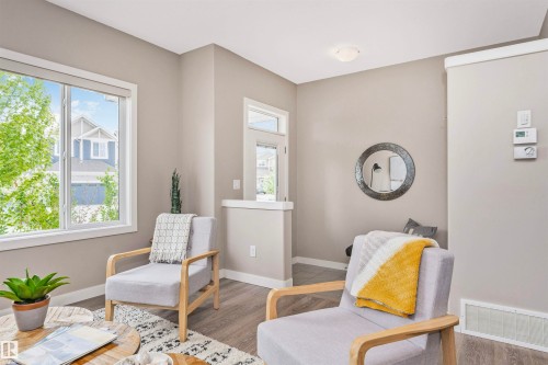 Bright interior space featuring neutral wall tones, white trim, wood-finish flooring, a contemporary flush-mount ceiling light, and prominent windows with white frames - 22124 85 Avenue, Edmonton, AB - Indoor
