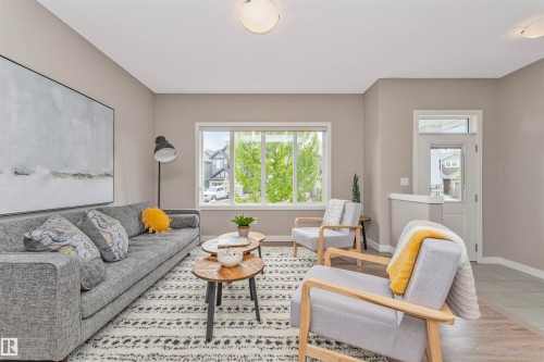 Living area featuring neutral wall paint, wood-finish flooring, and a large window with white trim - 22124 85 Avenue, Edmonton, AB - Indoor Photo Showing Living Room